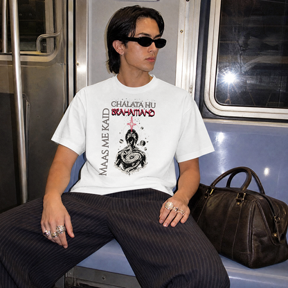 A person wearing a white graphic T-shirt with black and red text and artwork, seated on a train. The shirt reads  'MAAS ME KAID CHALATA HU BRAHAMAND'